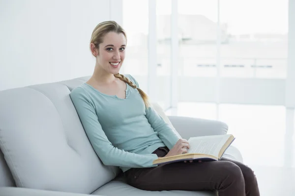 Schöne lässige Frau sitzt auf der Couch und liest ein Buch — Stockfoto