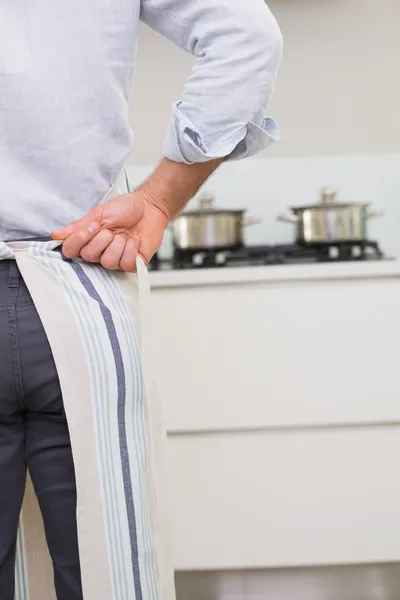 Mid section of man wearing apron in kitchen — Stock Photo, Image