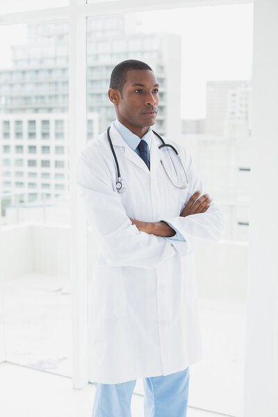 Serious doctor with arms crossed in a medical office