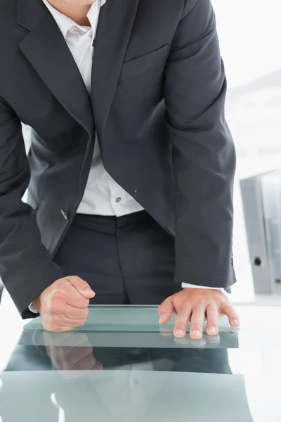 Mid section of businessman with clenched fist on office desk — Stock Photo, Image