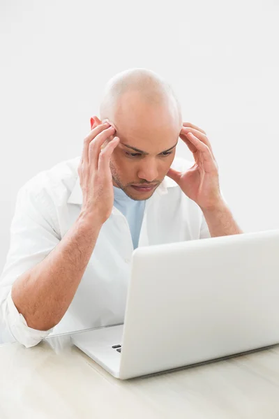 Geconcentreerd bezorgd casual man met laptop aan balie — Stockfoto