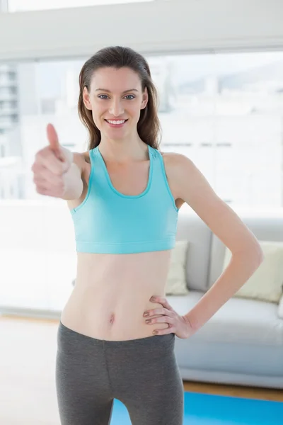 Durchtrainierte Frau gestikuliert Daumen hoch im Fitnessstudio — Stockfoto