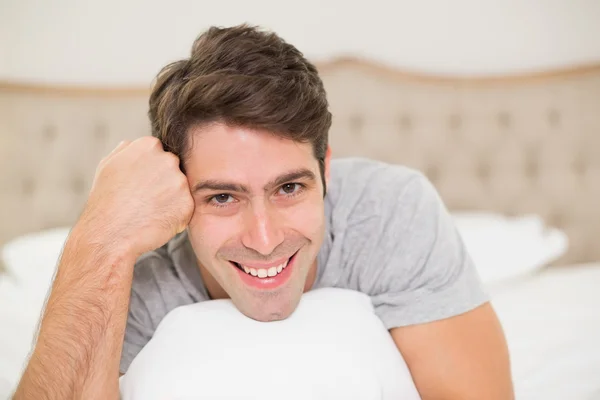 Close up portrait of a smiling man resting in bed — Stock Photo, Image