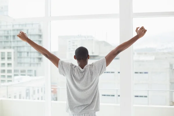 Rear view of Afro man stretching his arms near window — Stock Photo, Image