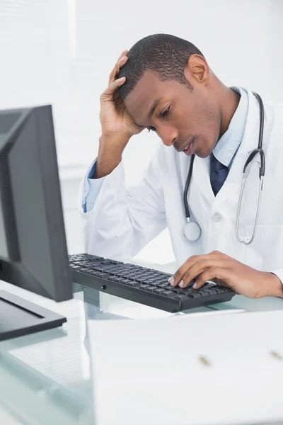 Besorgter männlicher Arzt nutzt Computer — Stockfoto