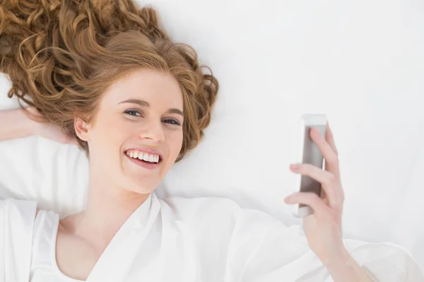 Rubia relajada mirando el teléfono móvil en la cama — Foto de Stock