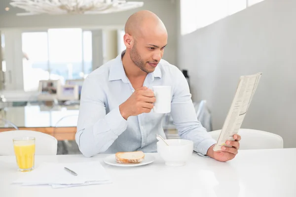 Człowiek pije kawę podczas czytania gazety w domu — Zdjęcie stockowe