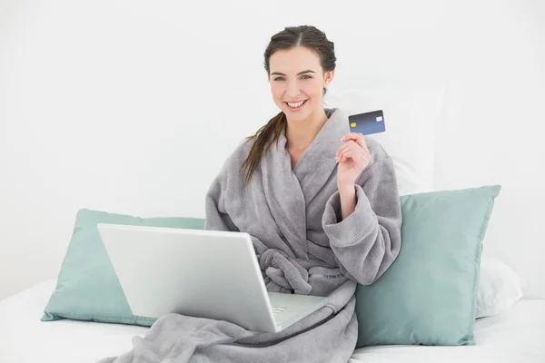 Excited woman in bathrobe doing online shopping in bed — Stock Photo, Image