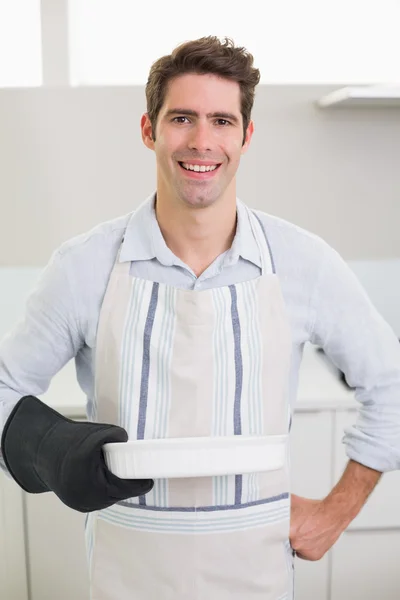 Man smelling food in baking dish in kitchen — Stock Photo, Image