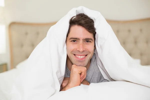 Close up portrait of a smiling man resting in bed — Stock Photo, Image