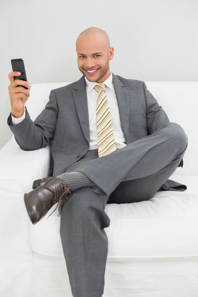 Businessman text messaging on sofa at home — Stock Photo, Image
