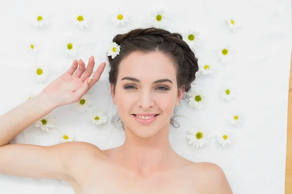 Schöne junge Frau mit Blumen im Schönheitssalon — Stockfoto