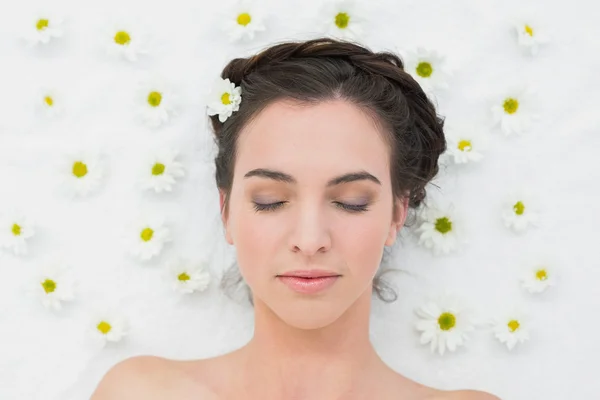 Hermosa mujer con los ojos cerrados y flores en salón de belleza — Foto de Stock