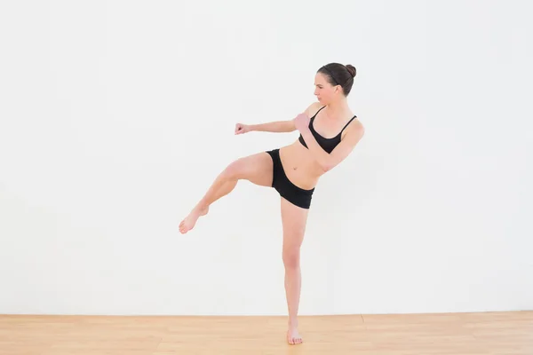 Deportiva mujer en forma realizando una patada de aire en el gimnasio —  Fotos de Stock