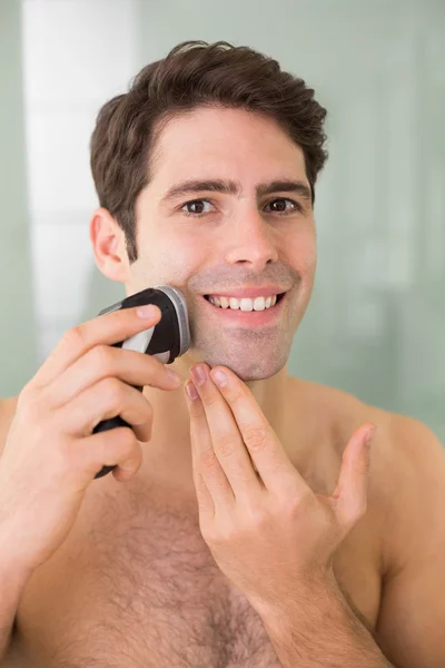 Sorridente bell'uomo senza camicia rasatura con rasoio elettrico — Foto Stock