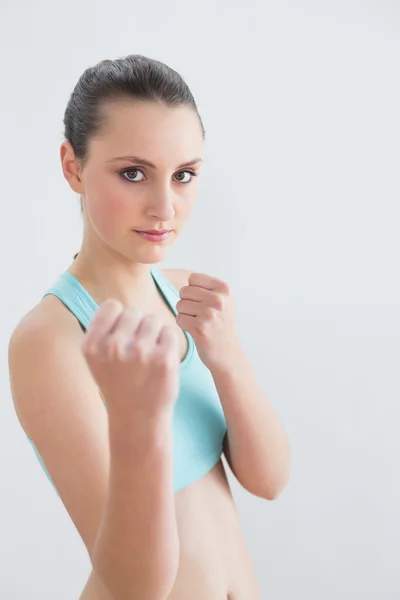 Lächelnde, fitte Frau ballt Fäuste gegen Wand — Stockfoto