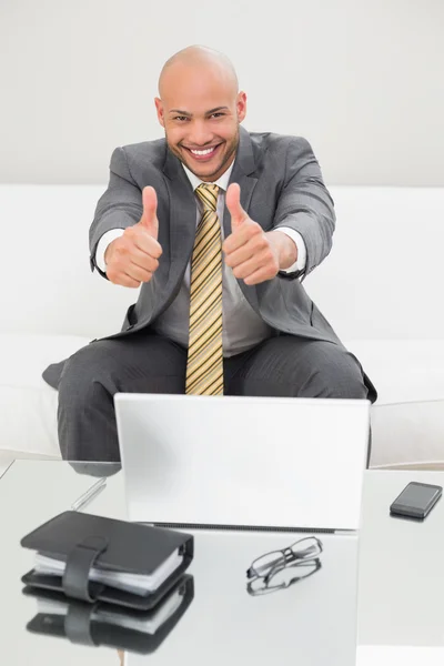 Elegante uomo d'affari gesticolare pollici con il computer portatile a casa — Foto Stock