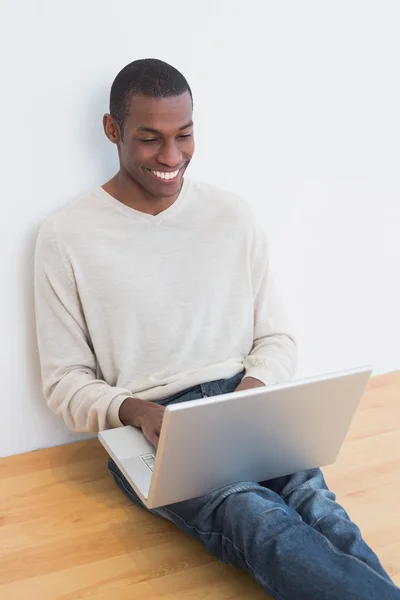 Happy casual Afro young man using laptop on floor — Stock Photo, Image