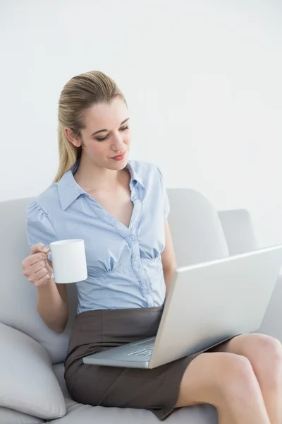 Preciosa mujer de negocios tranquila trabajando en un cuaderno sosteniendo una taza —  Fotos de Stock