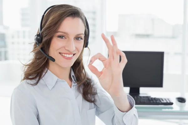 Affärskvinna bär headset samtidigt gestikulerande ok tecken i office — Stockfoto