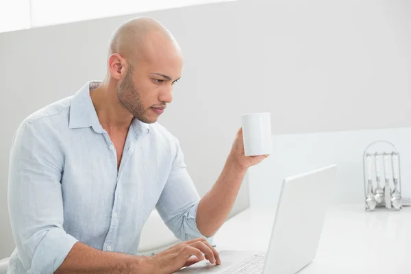 Concentrated casual man using laptop at home — Stock Photo, Image