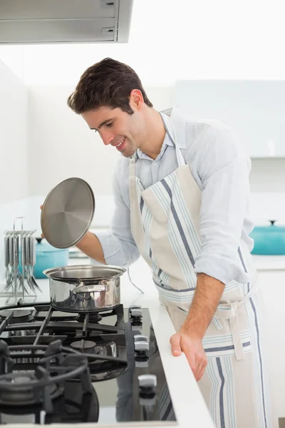 Souriant jeune homme préparant la nourriture dans la cuisine — Photo