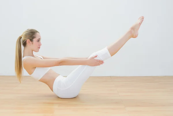 Sporty young woman doing sports exercise sitting on floor — Stock Photo, Image