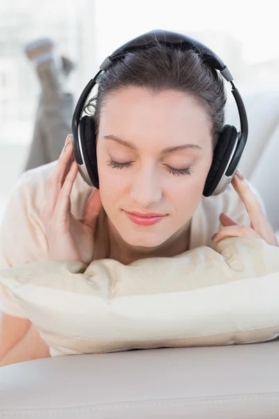 Närbild på en avslappnad casual kvinna njuter av musik på soffa — Stockfoto