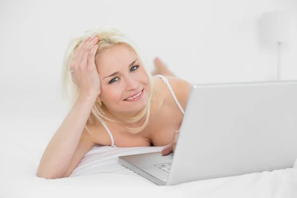 Avslappnad avslappnad blond med laptop i sängen — Stockfoto