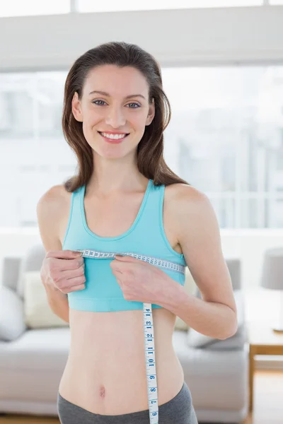 Mujer sonriente en ropa deportiva que mide el pecho en el gimnasio —  Fotos de Stock