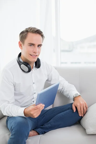 Casual leende ung man använder digital tablet på soffa — Stockfoto