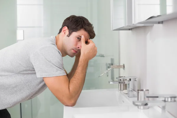 Напряженный молодой человек в умывальнике в ванной комнате — стоковое фото