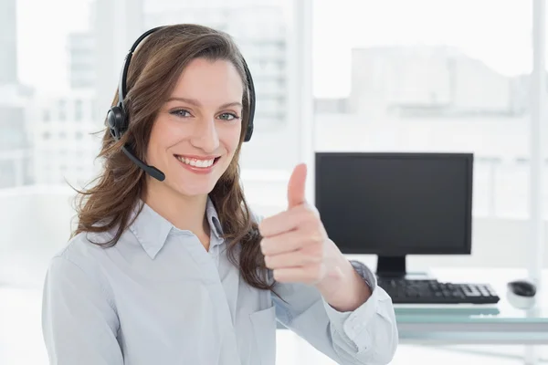 Mujer de negocios con auriculares mientras hace gestos con los pulgares hacia arriba en la oficina — Foto de Stock