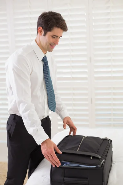 Businessman unpacking luggage at a hotel bedroom — Stock Photo, Image