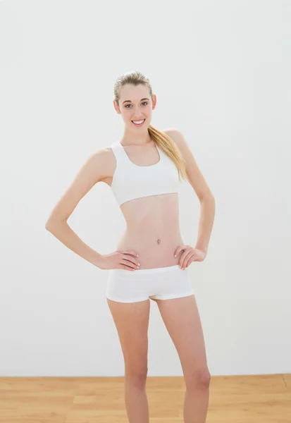 Mujer atractiva feliz posando con las manos en las caderas sonriendo a la cámara — Foto de Stock