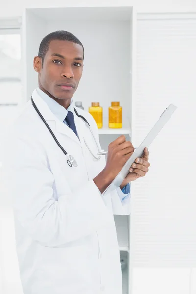 Serious doctor writing a prescription in medical office — Stock Photo, Image