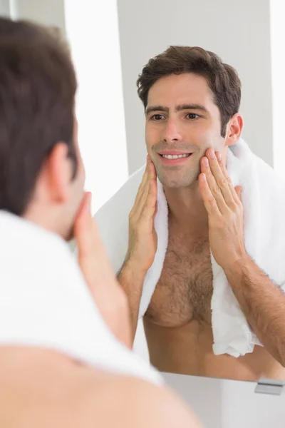 Вид сзади на человека, смотрящего на себя в зеркало ванной комнаты — стоковое фото