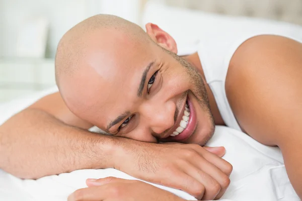 Uśmiechający się dorywczo łysy mężczyzna młody leżąc w łóżku — Zdjęcie stockowe
