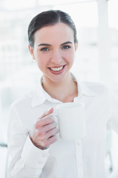 Elegante empresaria sosteniendo taza de café en la oficina — Foto de Stock