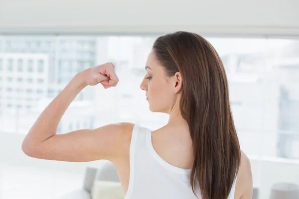 Fitte braunhaarige Frau lässt im Fitnessstudio Muskeln spielen — Stockfoto