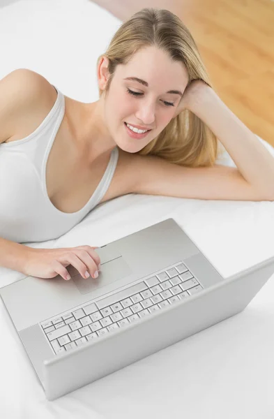 Lovely young woman using her notebook lying on her bed — Stock Photo, Image