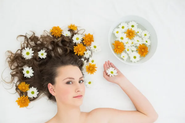 Belle femme couchée avec bol de fleurs dans un salon de beauté — Photo