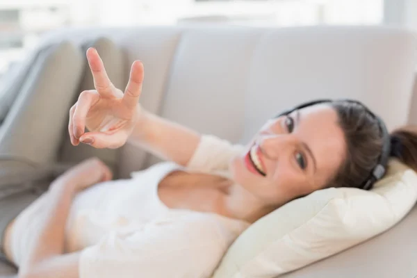 Vrolijke casual jonge vrouw genieten van muziek op sofa — Stockfoto