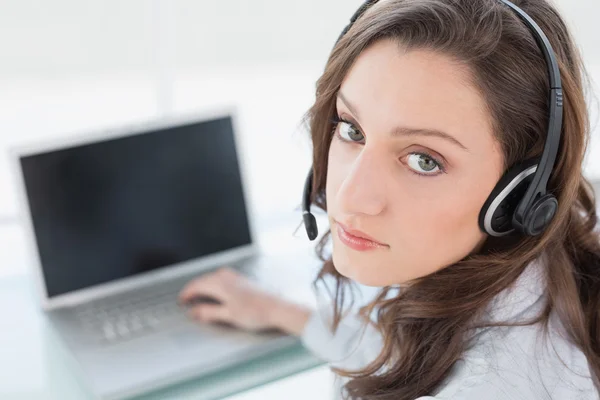 Serious businesswoman wearing headset in front of laptop — Stock Photo, Image