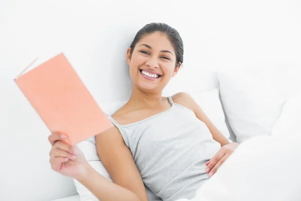 Cheerful woman reading a book in bed — Stock Photo, Image