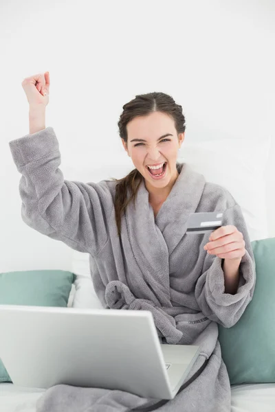 Opgewonden vrouw in badjas doen online winkelen in bed — Stockfoto