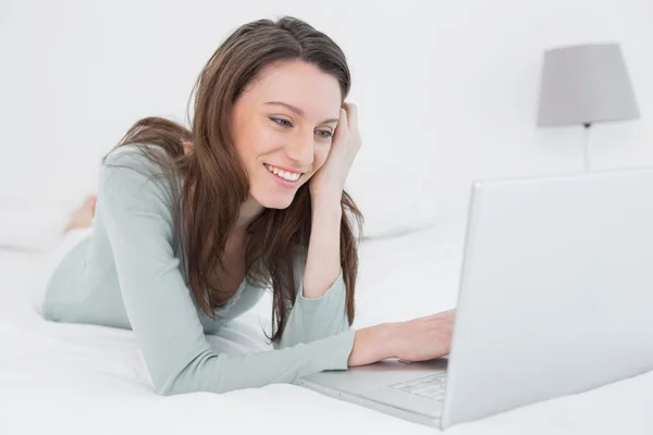 Cheerful relaxed casual woman with laptop in bed — Stock Photo, Image