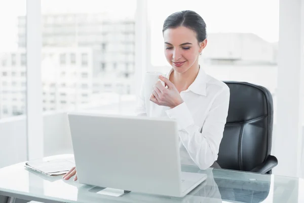 デスクでのノート パソコンを使用しながらコーヒーを飲む女性実業家 — ストック写真