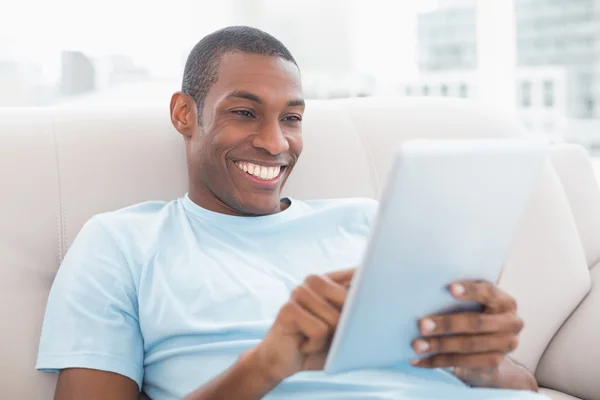 Casual smiling Afro man using digital tablet on sofa — Stock Photo, Image