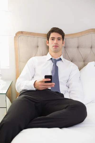 Ernste gut gekleidete Mann SMS-Nachrichten im Bett — Stockfoto